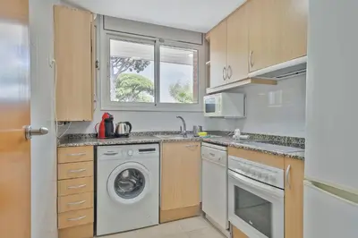 a kitchen with a washing machine and a window at Apartamentos Velor in Castelldefels
