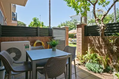 a patio with a table and chairs and a fence at Apartamentos Velor in Castelldefels