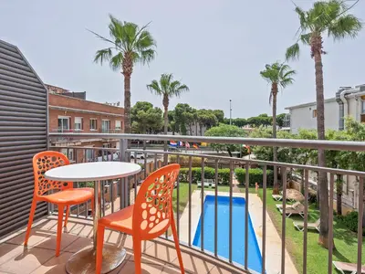 a balcony with a table and chairs and a pool at Apartamentos Velor in Castelldefels