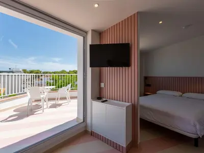 a bedroom with a bed and a balcony with a television at Apartamentos Sunway Atlanta in Sitges