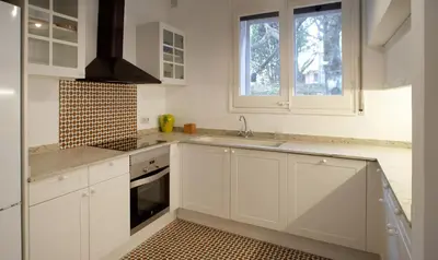 a kitchen with white cabinets and a sink and a window at Can Calixto in Aiguafreda