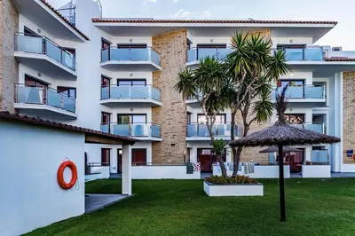 an apartment building with a garden and an umbrella at Apartamentos Sunway Apollo in Sitges