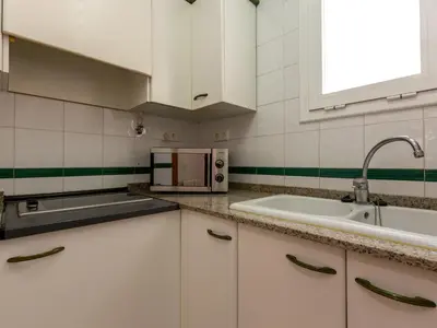 a white kitchen with a sink and a microwave at Apartamentos Sunway San Jorge in Sitges