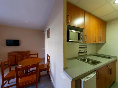 a small kitchen with a table and a sink at Apartamentos Sunway San Jorge in Sitges