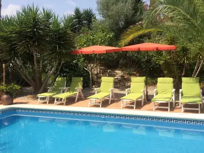 a group of chairs and umbrellas next to a swimming pool at Villa Rosa Sitges in Can Trabal