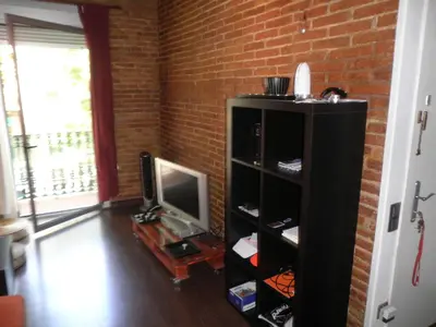 a living room with a tv and a brick wall at Bacrou apartment, design loft near the sea in Barcelona