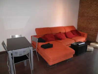 a living room with an orange couch and a table at Bacrou apartment, design loft near the sea in Barcelona
