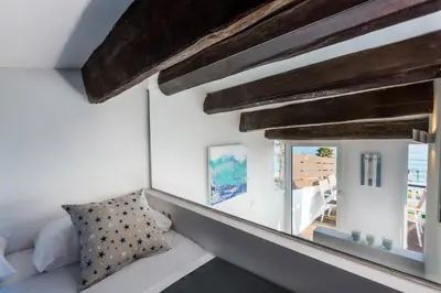 a bedroom with white walls and wooden beams at Vilasarmarlux II in Vilassar de Mar