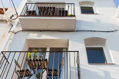 a white building with a balcony with a plant on it at Vilasarmarlux II in Vilassar de Mar