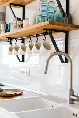 a bunch of coffee cups are on a shelf above a sink at Sitges Colonial - al lado de la playa in Sitges