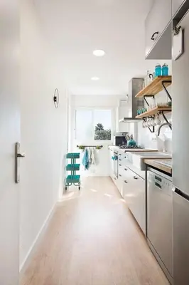 a kitchen with white cabinets and a blue chair in it at Sitges Colonial - al lado de la playa in Sitges