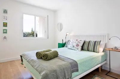 a white bedroom with a bed and a window at Sitges Colonial - al lado de la playa in Sitges