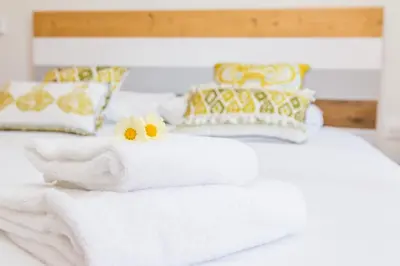 a white bed with towels and flowers on it at Rambla de Marisol Apartments in Castelldefels
