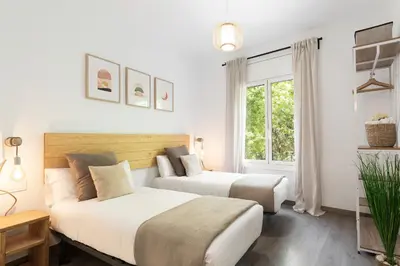 two beds in a white room with a window at KeyFamily Cozy Home in Barcelona