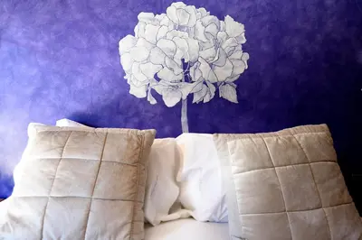 a bed with a flower on a purple wall at Boutique hotel Urbisol in Calders