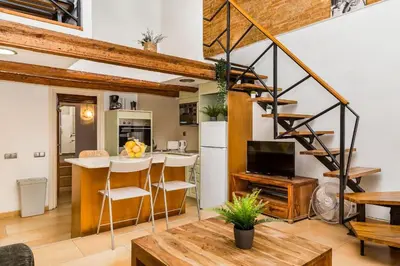 a kitchen and living room with a spiral staircase at Fridays Flats Dreamy Duplex - Stylish Beach Loft in Barcelona