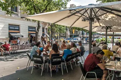 a group of people sitting at an outdoor restaurant at Habitat Apartments Paseo de Gracia Suite in Barcelona