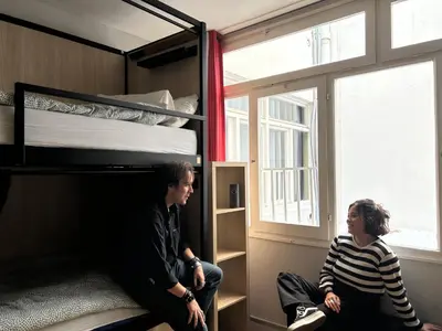 a man and a woman sitting in a bunk bed at Onefam Les Corts in Barcelona