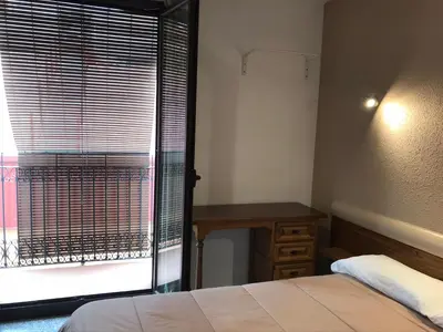 a bedroom with a bed and a desk and a window at Hostal Radio Barcelona in Barcelona
