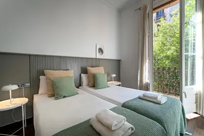 a bedroom with two beds and a large window at Habitat Apartments Eixample Balconies. in Barcelona