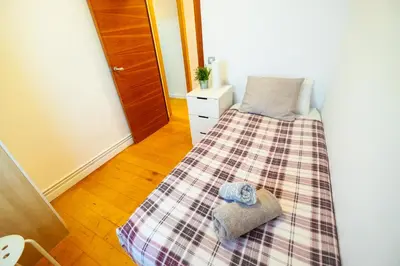 a small bedroom with a bed with a plaid blanket at RentBCN Park Guell in Barcelona