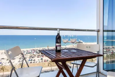 a table with wine glasses and a view of the beach at 1410 - Mediterranean Forum Apartment in Barcelona