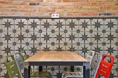 a table and chairs in front of a tiled wall at Hola Hostal Collblanc in Hospitalet de Llobregat