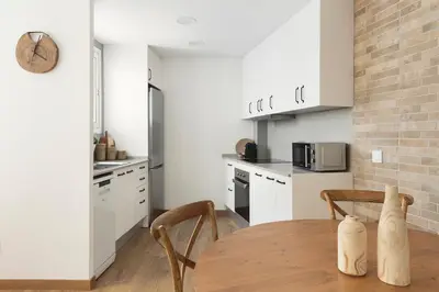 a kitchen with white cabinets and a wooden table at KeyFamily Sweet Home in Barcelona