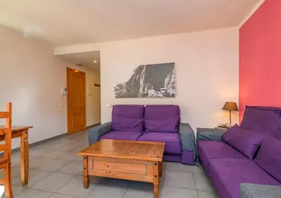 a living room with purple couches and a table at Apartaments Rural Montseny in gualba de Dalt