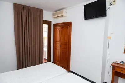 a bedroom with a bed and a television on a wall at Hotel Haromar in Calella
