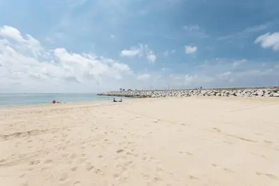 a beach with people laying on the sand at Matarolux 14 in Mataró