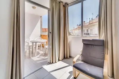 a living room with a chair and a balcony at Hauzify I Apartaments Sot del Morer in San Pol de Mar