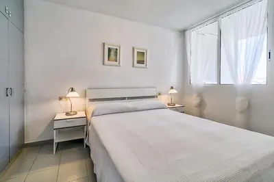 a white bedroom with a large bed and a window at Hauzify I Apartaments Sot del Morer in San Pol de Mar