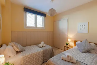 a bedroom with two beds and a window at Sitges Holiday Apartment in Sitges