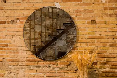 a round mirror on the side of a brick wall at Novus Homes Barcelona Poble Sec in Barcelona