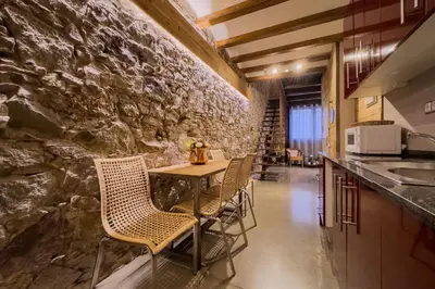 a table and chairs in a kitchen with a stone wall at Novus Homes Barcelona Poble Sec in Barcelona