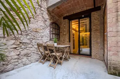 a patio with a table and chairs next to a stone wall at Novus Homes Barcelona Poble Sec in Barcelona