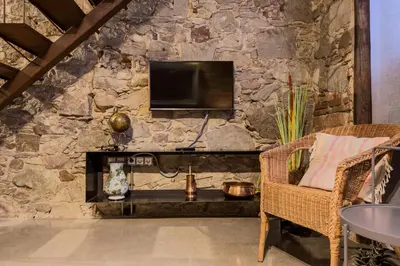 a stone wall with a television and a chair at Novus Homes Barcelona Poble Sec in Barcelona