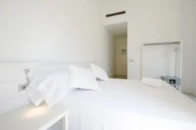a white bedroom with a white bed with white pillows at Express by gaiarooms in Barcelona
