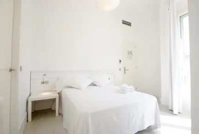 a white bedroom with a white bed and a window at Express by gaiarooms in Barcelona