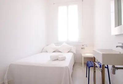 a white bedroom with a bed and a sink at Express by gaiarooms in Barcelona