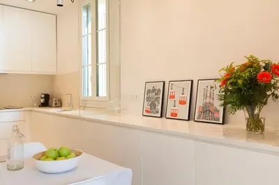 a white kitchen with a bowl of apples and flowers at Click&Flat Luxury Sant Joan in Barcelona