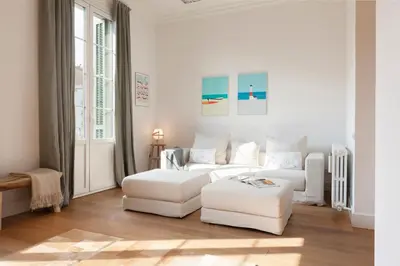 a white living room with a couch and a stool at Click&Flat Luxury Sant Joan in Barcelona