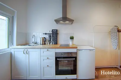 a kitchen with white cabinets and a stove top oven at Hotelito Boutique Badalona. in Badalona