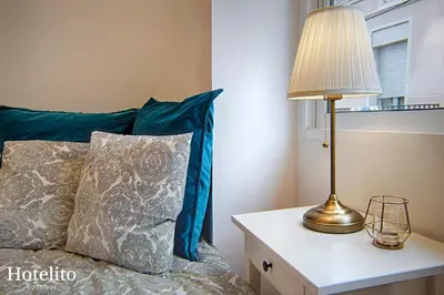 a lamp on a table next to a bed with blue pillows at Hotelito Boutique Badalona. in Badalona