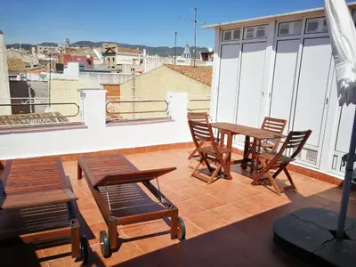 a patio with wooden tables and chairs on a roof at Hotelito Boutique Badalona. in Badalona