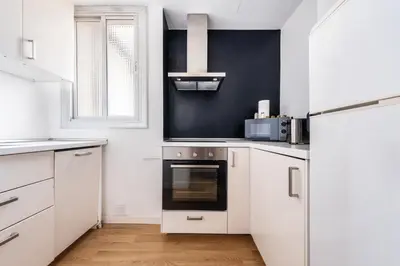 a kitchen with white cabinets and a black wall at AinB Barcelona Sants Apartments in Barcelona