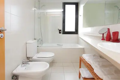 a white bathroom with a toilet and a sink at 1216 - Forum Gardens Apartment in Barcelona