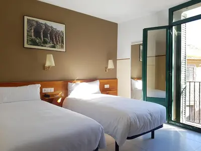 a hotel room with two beds and a window at El Jardi in Barcelona