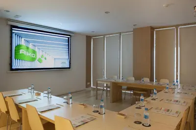 a conference room with tables and chairs and a screen at Ako Suite Hotel in Barcelona